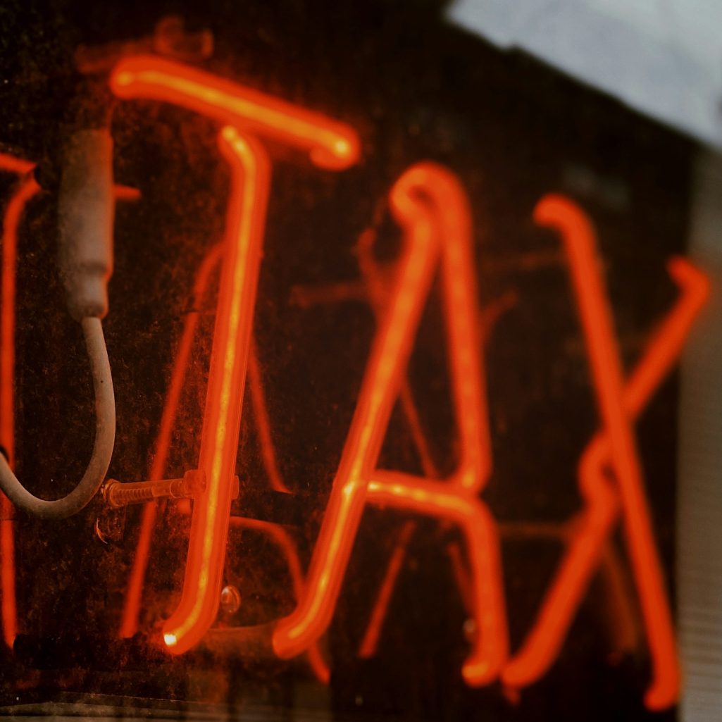 Tax Neonzeichen mit der Aufschrift "TAX" in knalligem Rot.